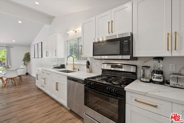 kitchen featuring vaulted ceiling with beams, white cabinets, stainless steel appliances, and light wood-type flooring