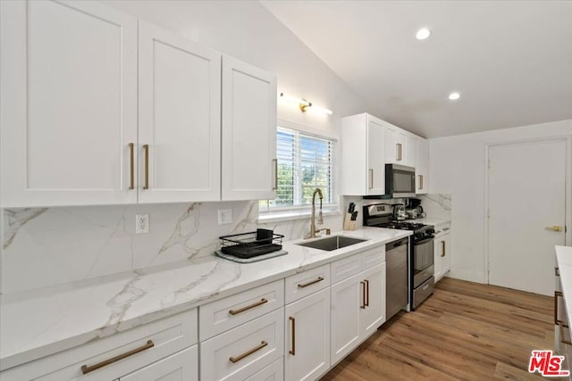 kitchen featuring stainless steel appliances, tasteful backsplash, light wood-type flooring, and white cabinets