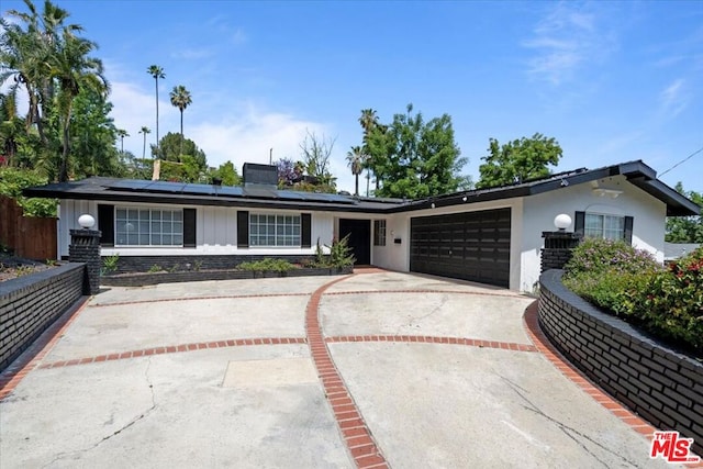 ranch-style home with a garage and solar panels