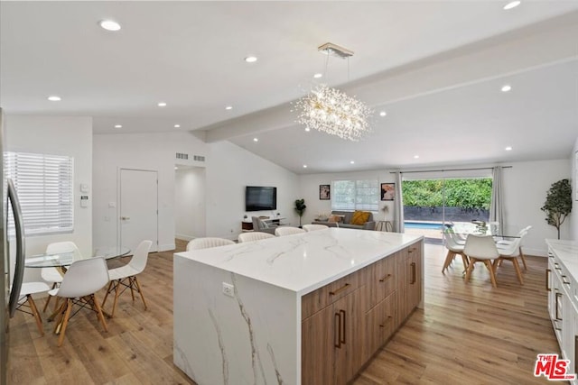 kitchen with pendant lighting, light wood-type flooring, a center island, and vaulted ceiling with beams