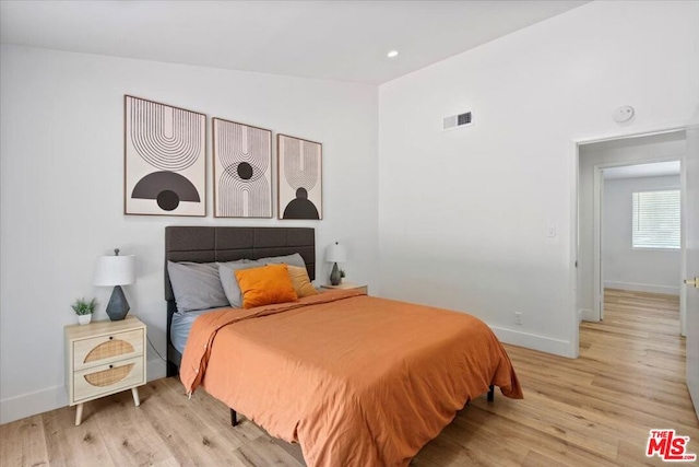 bedroom with vaulted ceiling and light hardwood / wood-style floors