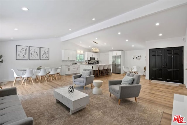 living room with vaulted ceiling with beams and light hardwood / wood-style flooring