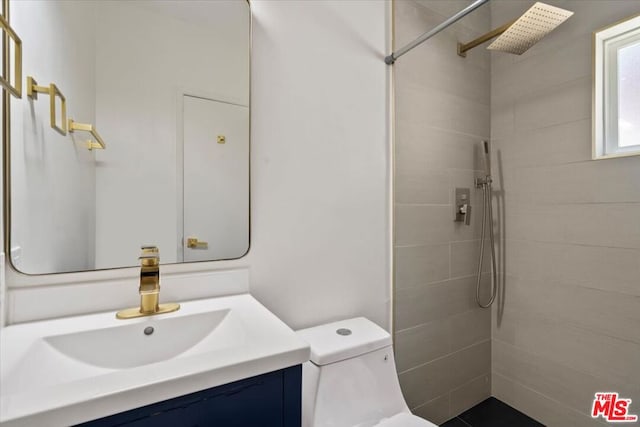 bathroom with vanity, a tile shower, and toilet