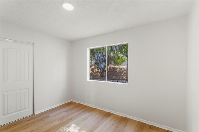 unfurnished room with a textured ceiling and light wood-type flooring