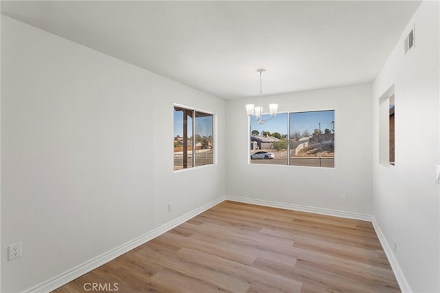 unfurnished dining area featuring a notable chandelier and light hardwood / wood-style flooring