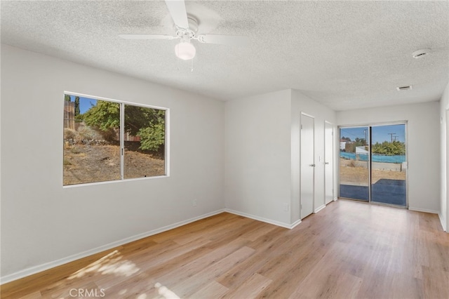 spare room featuring plenty of natural light, a textured ceiling, and light hardwood / wood-style flooring