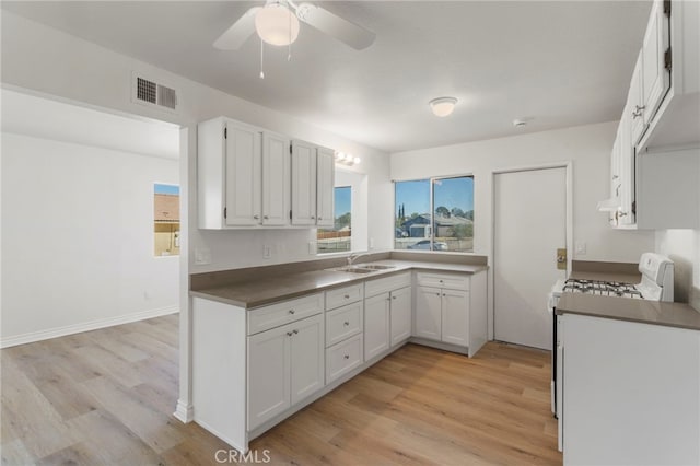 kitchen featuring sink, white cabinets, white stove, and light hardwood / wood-style flooring