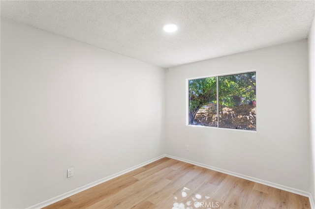 spare room with a textured ceiling and light wood-type flooring