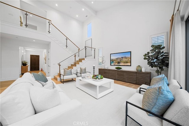 living room with light wood-type flooring and a towering ceiling