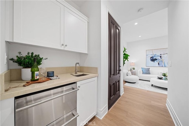 bar with white cabinetry, dishwasher, sink, and light wood-type flooring