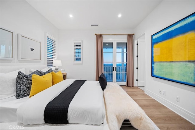 bedroom with access to exterior, french doors, multiple windows, and light wood-type flooring