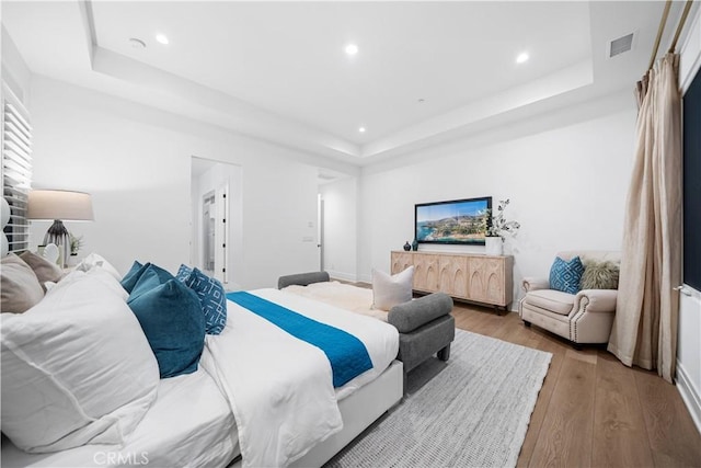 bedroom with a raised ceiling and wood-type flooring