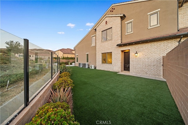 rear view of property featuring a yard and central AC unit