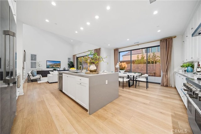 kitchen featuring sink, white cabinetry, a kitchen island with sink, and light hardwood / wood-style flooring