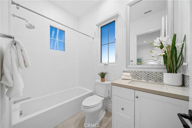 full bathroom with backsplash, vanity, tiled shower / bath combo, and toilet