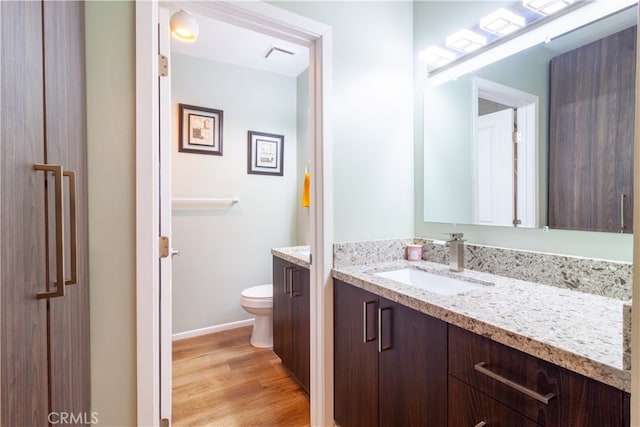 bathroom featuring toilet, vanity, and wood-type flooring