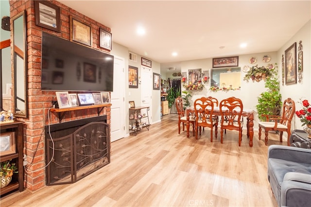 dining space featuring light wood-type flooring and a brick fireplace