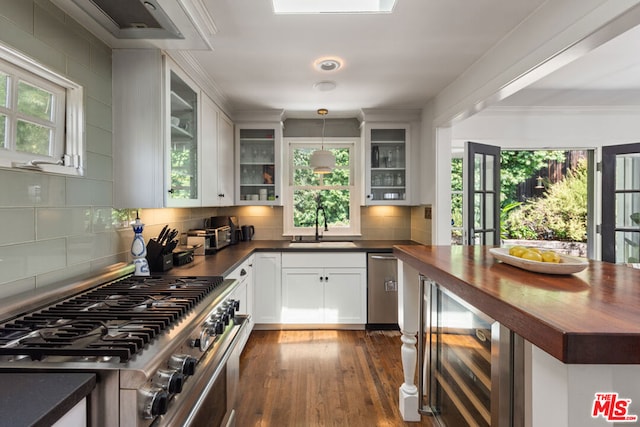 kitchen featuring stainless steel appliances, sink, decorative light fixtures, white cabinetry, and wine cooler