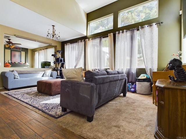 living room with ceiling fan with notable chandelier and hardwood / wood-style flooring