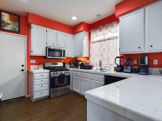 kitchen with dark hardwood / wood-style flooring, stainless steel appliances, sink, tile countertops, and white cabinets