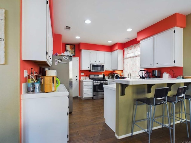 kitchen featuring kitchen peninsula, dark hardwood / wood-style flooring, white cabinets, and appliances with stainless steel finishes