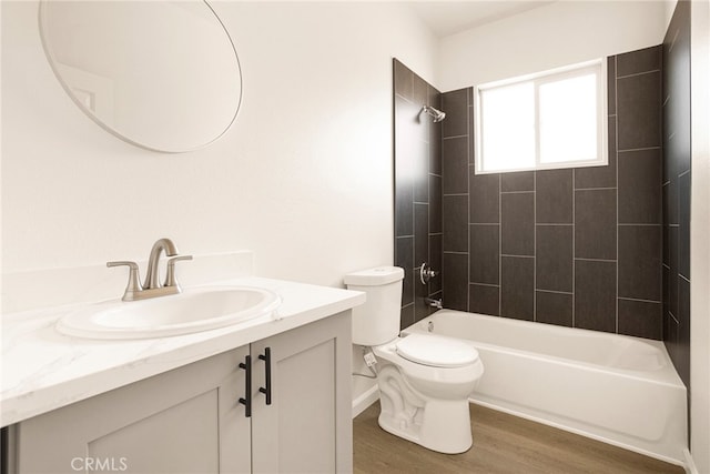 full bathroom with tiled shower / bath, vanity, hardwood / wood-style flooring, and toilet