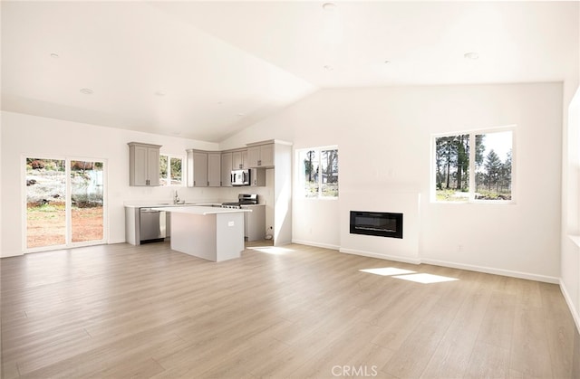 unfurnished living room featuring light hardwood / wood-style floors, heating unit, high vaulted ceiling, and sink