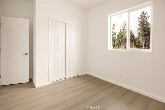 unfurnished bedroom with a closet and light hardwood / wood-style floors