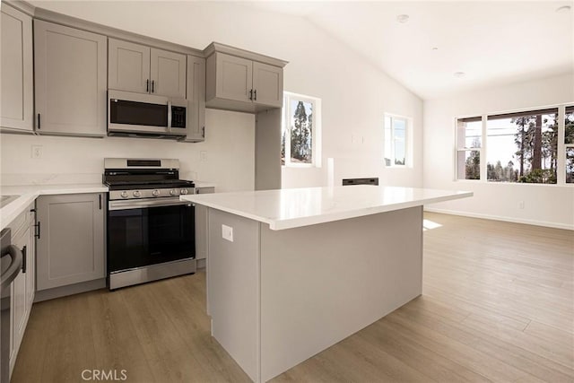 13990 Pineland Cir, Magalia, CA 95954 - kitchen featuring stainless steel appliances, gray cabinetry, lofted ceiling, light wood finished floors, and a center island