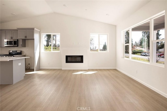 13990 Pineland Cir, Magalia, CA 95954 - unfurnished living room with vaulted ceiling, light wood finished floors, a glass covered fireplace, and baseboards