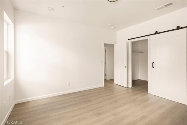 13990 Pineland Cir, Magalia, CA 95954 - unfurnished bedroom with light wood-type flooring, a closet, baseboards, and a barn door