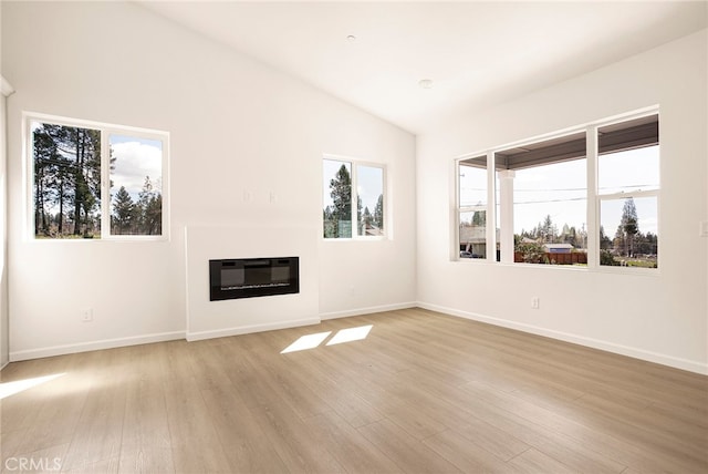unfurnished living room with a wealth of natural light, lofted ceiling, and light hardwood / wood-style flooring