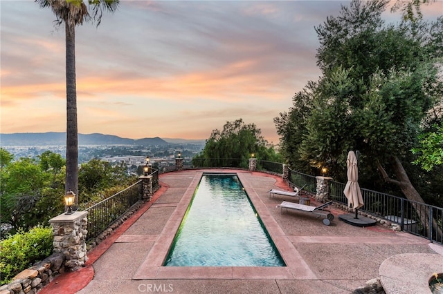 pool at dusk featuring a patio area and a mountain view