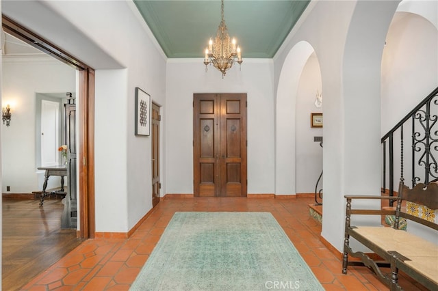 entrance foyer with ornamental molding, light parquet floors, and an inviting chandelier