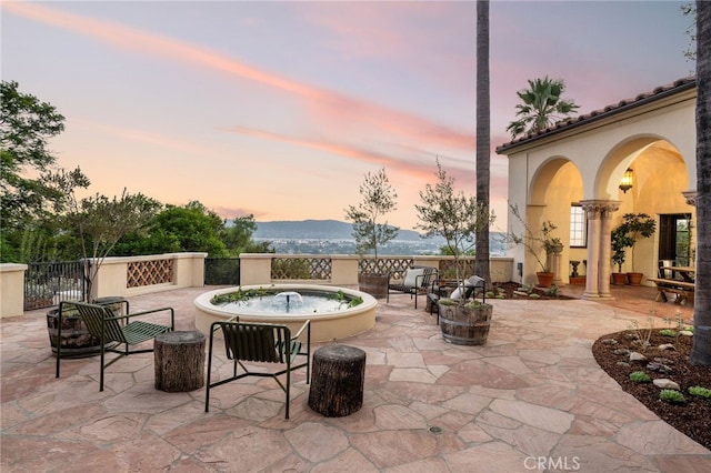 patio terrace at dusk with a hot tub and a mountain view