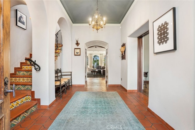 corridor with crown molding, a chandelier, and dark tile patterned flooring