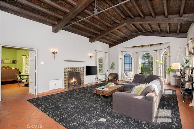 living room with beam ceiling, high vaulted ceiling, and a tile fireplace