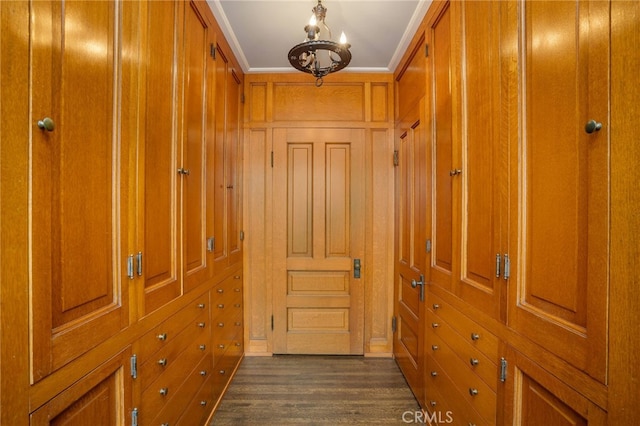 hallway featuring an inviting chandelier, dark wood-type flooring, and crown molding