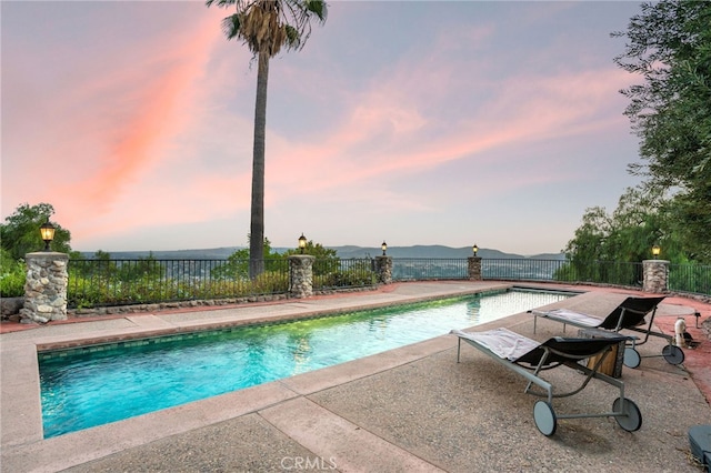 pool at dusk featuring a patio area