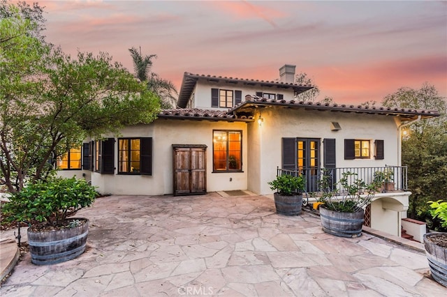 back house at dusk featuring a patio