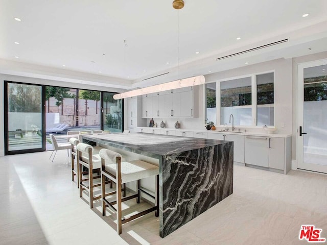 kitchen featuring a healthy amount of sunlight, a kitchen island, sink, and dark stone counters