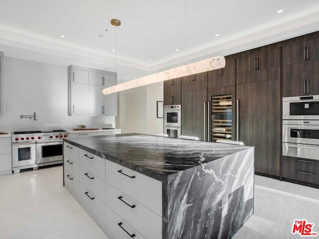 kitchen with white cabinets, dark stone counters, stainless steel appliances, and a large island