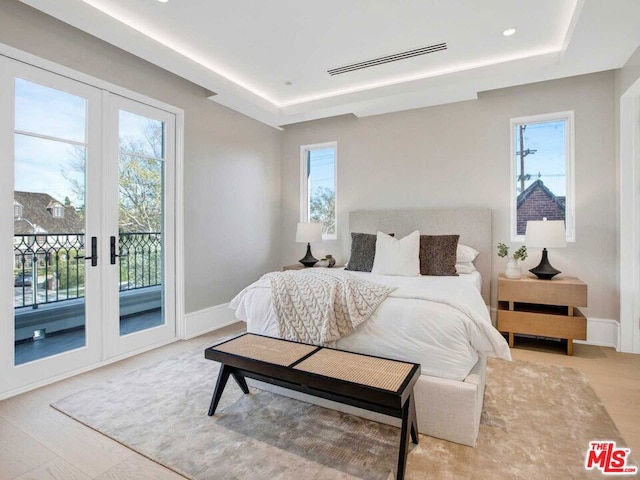 bedroom featuring a raised ceiling, access to exterior, and french doors