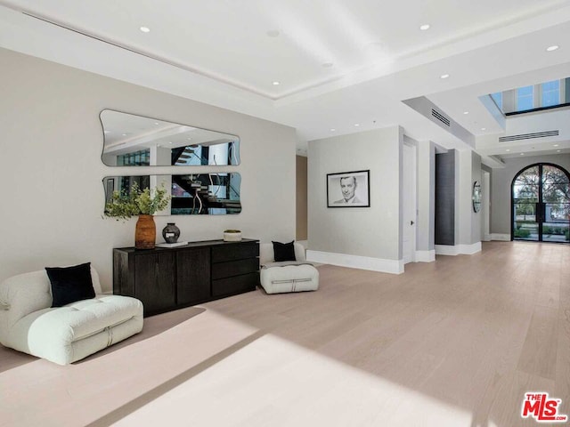 living area with light wood-type flooring and a raised ceiling