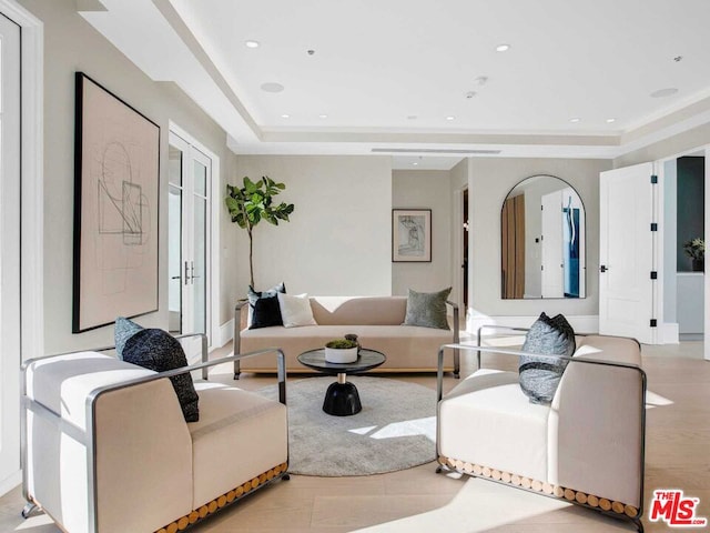 living room with a raised ceiling, light hardwood / wood-style flooring, and french doors