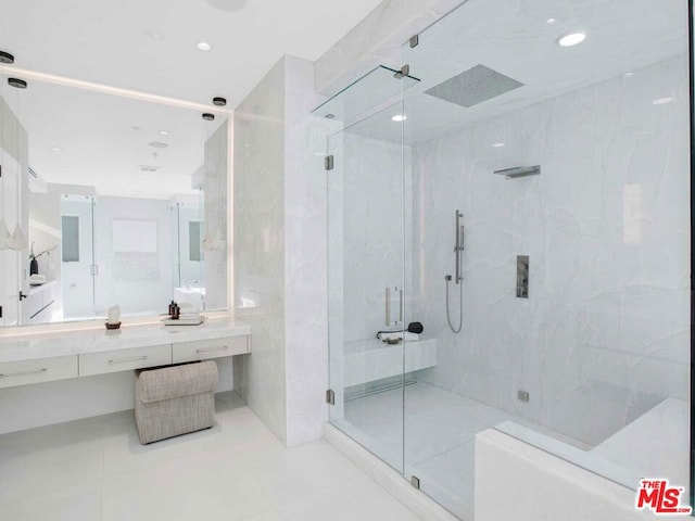 bathroom featuring tile patterned floors, vanity, a shower with shower door, and tile walls