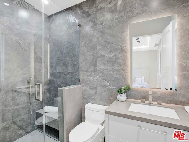 bathroom featuring vanity, toilet, a shower with shower door, and tile walls