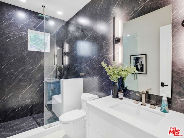 bathroom with tiled shower, vanity, tile walls, and toilet