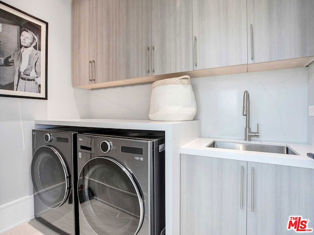 clothes washing area featuring cabinets, sink, and washing machine and clothes dryer