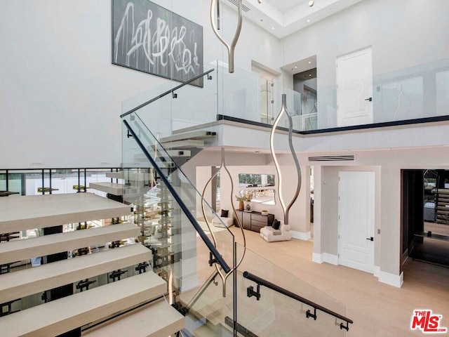 stairs featuring wood-type flooring and a high ceiling